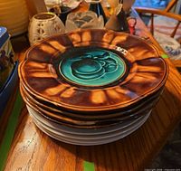 stack of majolica plates showing brown rim and turquoise fruit design
