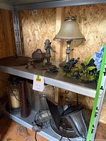 Full view of two shelves showing assorted lamp, figurine, lantern, funnel, pitcher and other decor