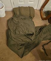 Two olive drab military sleeping bags on floor