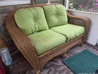 Front view of wicker loveseat with green cushions