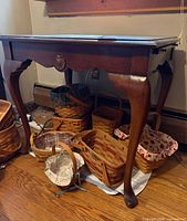 Full view of table front showing cabriole legs, baskets underneath for scale