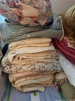 Stack of folded quilts showing multiple colors and patterns, top zip bag with patchwork quilt