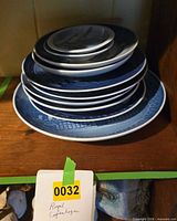 Stack of nine blue and white collector plates on shelf