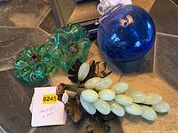 All four items grouped: stone grape bunch, blue glass orb, two green glass tiebacks