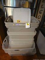 Stacked grouping of beige and clear totes with one beige lid displayed
