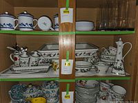 Cabinet shelves showing full assortment of Portmeirion pieces, blue-white bowls and clear tumblers