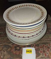 Stack of assorted plates showing top Syracuse floral rim plate and various banded designs