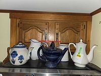 Group shot of all five teapots and pitchers on countertop