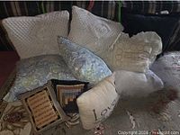 Group shot showing most pillows: two white crochet, blue-green paisley, black, ruffled "Home Sweet", patchwork, poem, and "Love" pillows