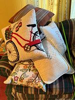 Group of pillows stacked on couch showing bicycle, floral, knit, striped designs
