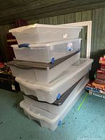 Stack of six clear underbed bins showing lids and wheels