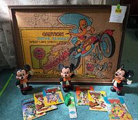 Full lot showing three Mickey Mouse banks, six MOTU mini-comics and framed burlap wall art