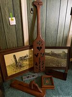 Group shot showing all items: two framed prints, wooden paddle decor, boot jack, wall rack, small floral picture