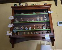 Front view of wooden display cabinet hung on wall showing four shelves and glass door