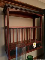 Full view of wood wall shelf hanging, spindle front, drawers visible