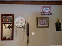 Overall wall view showing mirror, plate with hanger, candle sconce, framed prints and bottle vase
