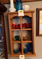 Front view of oak two-column wall shelf with glassware inside (contents not included)