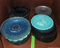 Stacks of assorted coloured mini glass plates in cabinet