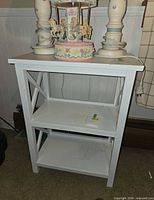 Front view of white three-tier side table with items on top (not included)