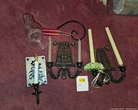 Multiple sconces, glass chimney, candles and hook displayed on carpet