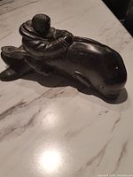 Full view of stone sculpture showing figure atop whale