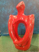 Front view of abstract red figurine showing oval opening and arms