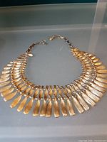 Full view of the brushed gold-tone petal necklace laid flat
