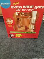 Front of retail box showing Carlson extra-wide gate with pet door