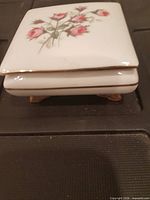 Square lidded porcelain trinket box showing rose decoration and gold trim