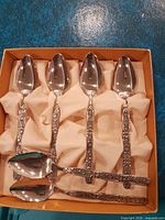 Set of six ornate stainless steel spoons in box