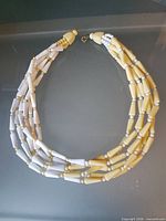 Full view of multi-strand cream and yellow necklace