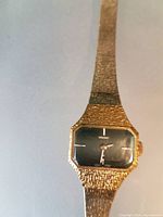 Front view of Seiko gold-tone wristwatch displaying rectangular dial and textured band