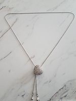 Full view of silver-tone lariat necklace with heart pendant and dangling ends