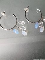 Front view of both hoop earrings showing dangling clear and blue crystals