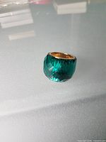 front view of emerald-green faceted crystal ring showing gold-tone interior