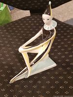 Full view of seated porcelain clown figurine on chair