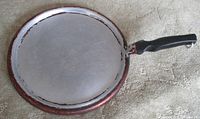 Top view of round aluminum griddle showing cooking surface and red outer rim