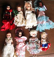 Group shot of eight antique dolls laid out showing size and outfits
