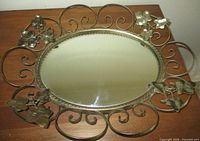 Full view of Syroco oval mirror showing entire metal scrollwork frame and ivy leaves
