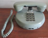 Full view of mint green Northern Telecom telephone showing handset, coiled cord and round base
