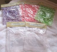 Five sealed packages of assorted colour drawstring bags displayed on towel