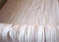 Full view of folded ivory ridged fabric showing overall texture and stripe pattern