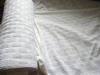 Roll of white embossed cable grid fabric with portion unrolled