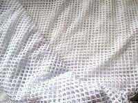 Close view of white fabric showing small square cut-out grid pattern