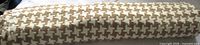 Rolled bolt of camel and cream houndstooth knit fabric