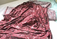 Bolt with burgundy printed knit fabric draped over grey print fabric