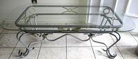 Full view of glass-top coffee table showing scrolled metal base