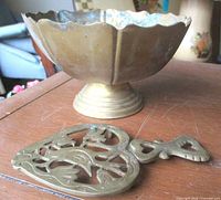 Brass pedestal bowl and bird motif trivet on tabletop
