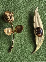 Both brooches side by side on green background