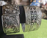 Front view of both silvertone bracelets on stand
